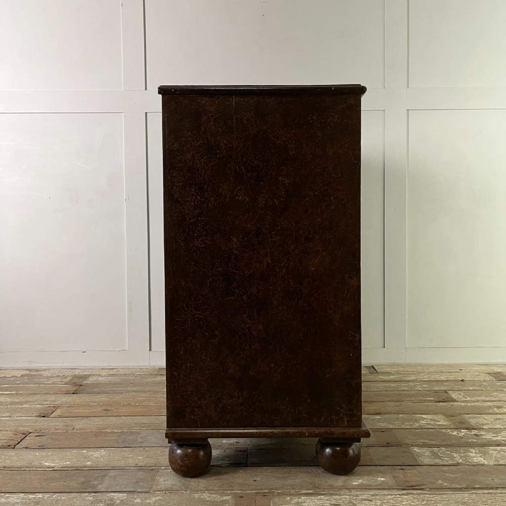 A nineteenth-century scumble-painted pine chest of drawers with decorative faux inlay lines, dark turned handles, and ball feet. View XIX