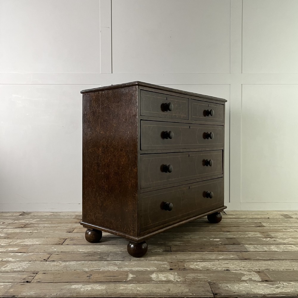 A nineteenth-century scumble-painted pine chest of drawers with decorative faux inlay lines, dark turned handles, and ball feet. View XX
