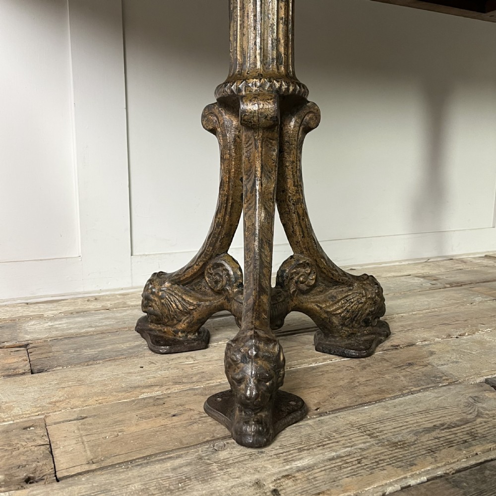 A long rectangular Victorian oak table featuring a thick wooden top resting on two ornate cast-iron pedestal legs. View III