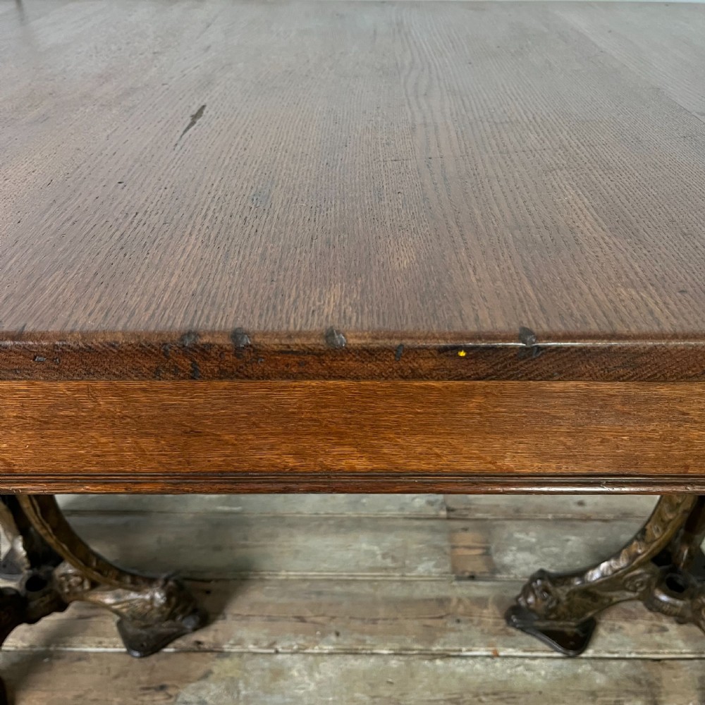 A long rectangular Victorian oak table featuring a thick wooden top resting on two ornate cast-iron pedestal legs. View XV