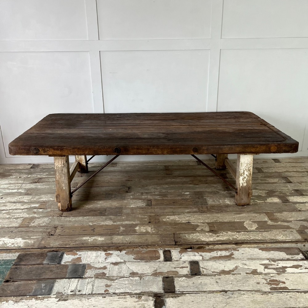 An early 20th-century rustic cheese press table featuring a thick dark wooden top and distressed painted trestle legs with metal bracing. View III