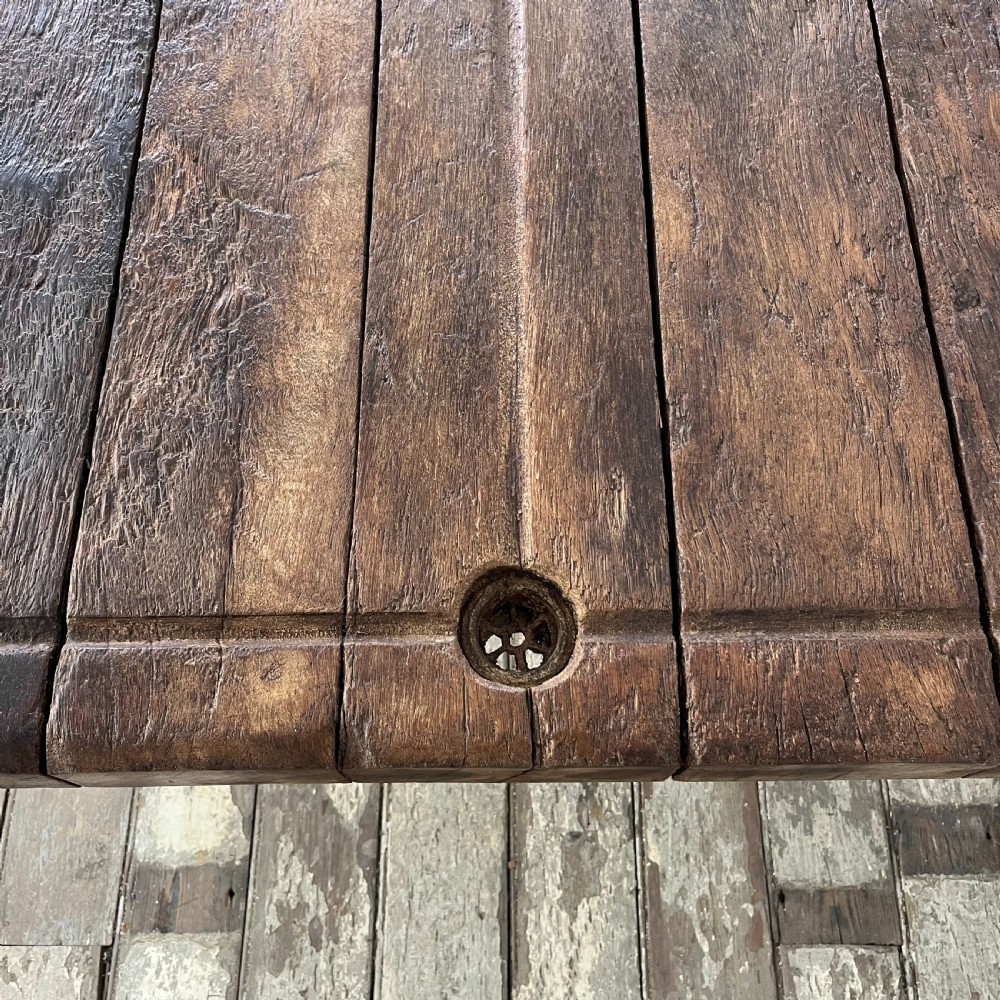 An early 20th-century rustic cheese press table featuring a thick dark wooden top and distressed painted trestle legs with metal bracing. View VII