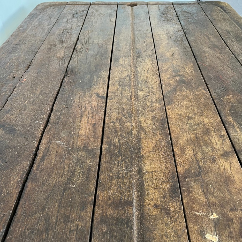 An early 20th-century rustic cheese press table featuring a thick dark wooden top and distressed painted trestle legs with metal bracing. View XIII