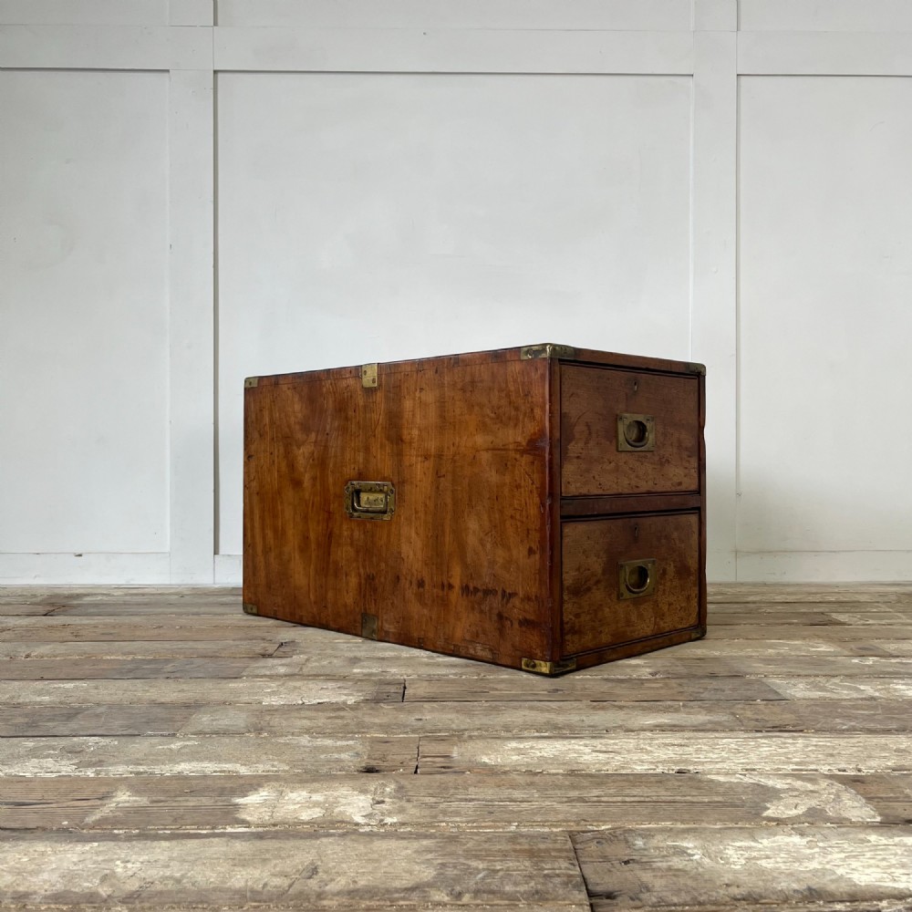 A nineteenth-century rectangular wooden desktop campaign chest featuring two drawers, flush brass drop handles, and brass corner straps.