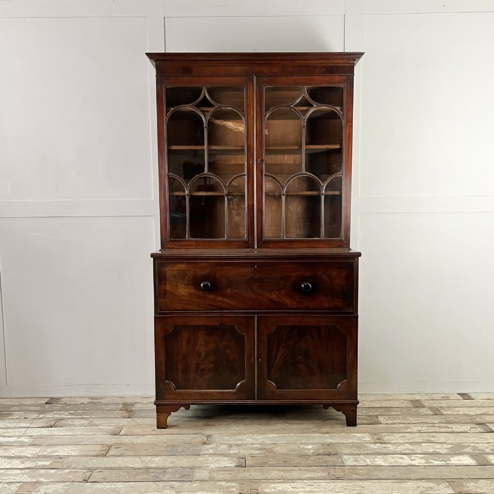 A dark mahogany George III secretaire bookcase featuring upper astragal glazed doors, a fold-out secretaire desk section with green leather insert, and lower cupboard doors on bracket feet. View II