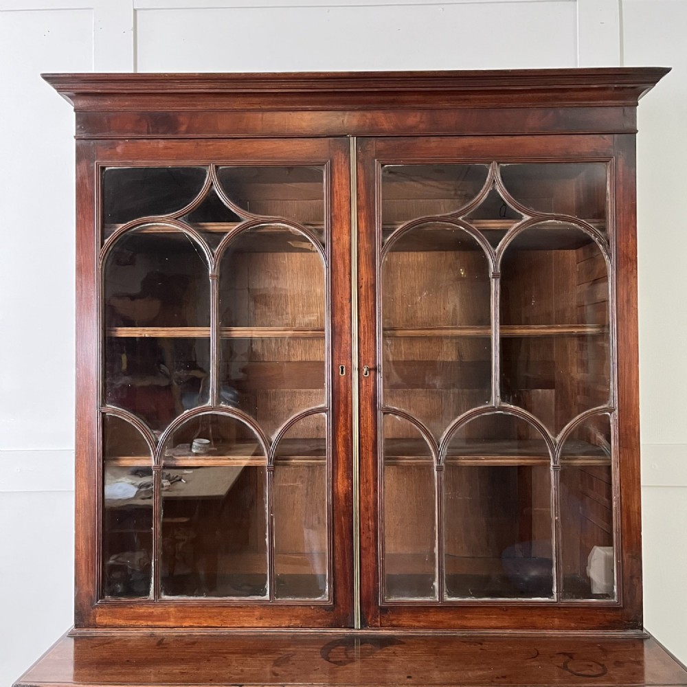 A dark mahogany George III secretaire bookcase featuring upper astragal glazed doors, a fold-out secretaire desk section with green leather insert, and lower cupboard doors on bracket feet. View III