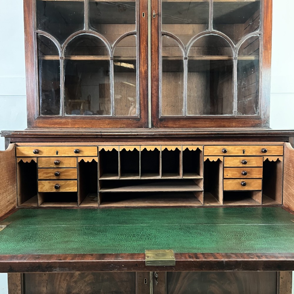 A dark mahogany George III secretaire bookcase featuring upper astragal glazed doors, a fold-out secretaire desk section with green leather insert, and lower cupboard doors on bracket feet. View IV