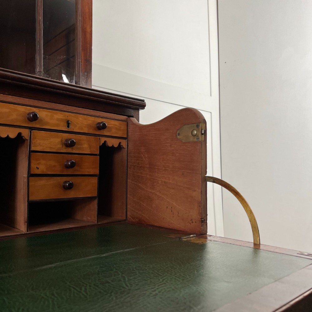 A dark mahogany George III secretaire bookcase featuring upper astragal glazed doors, a fold-out secretaire desk section with green leather insert, and lower cupboard doors on bracket feet. View V