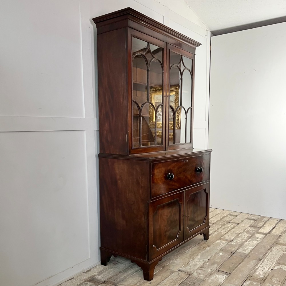 A dark mahogany George III secretaire bookcase featuring upper astragal glazed doors, a fold-out secretaire desk section with green leather insert, and lower cupboard doors on bracket feet. View VII