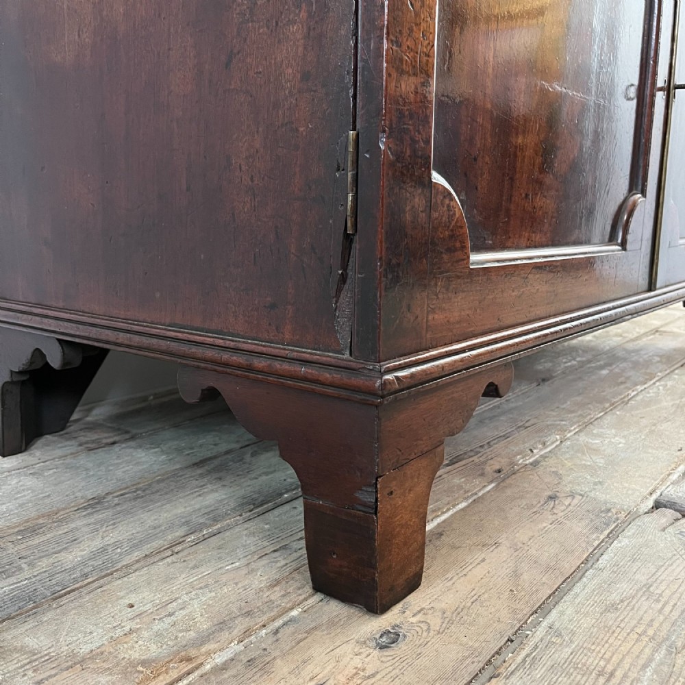 A dark mahogany George III secretaire bookcase featuring upper astragal glazed doors, a fold-out secretaire desk section with green leather insert, and lower cupboard doors on bracket feet. View IX