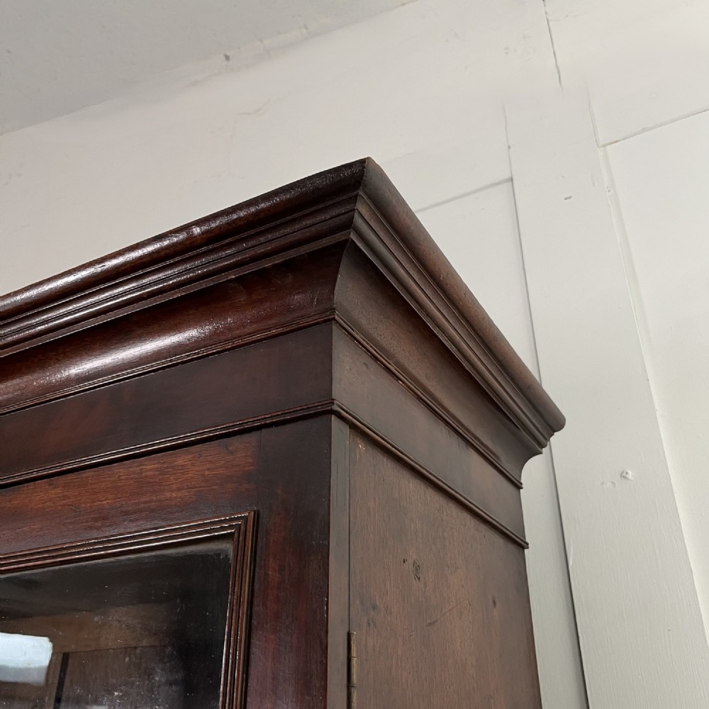 A dark mahogany George III secretaire bookcase featuring upper astragal glazed doors, a fold-out secretaire desk section with green leather insert, and lower cupboard doors on bracket feet. View X