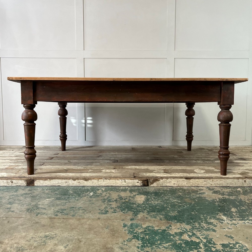 A large Victorian pine farmhouse table featuring a light natural wood plank top supported by dark brown turned wooden legs.