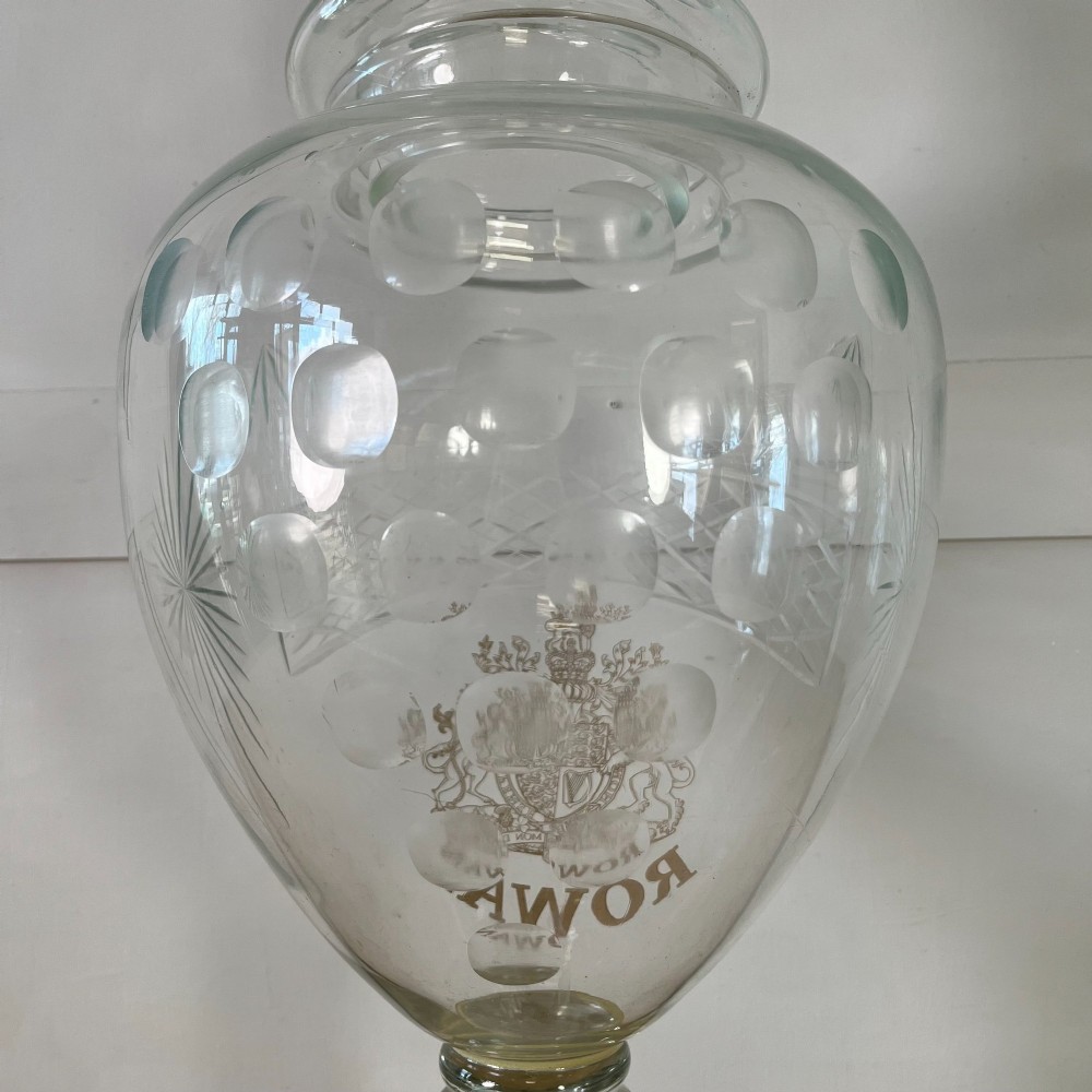 A clear cut glass Edwardian apothecary jar with a pointed finial lid, lattice shoulder pattern, and printed crest above the text ROWAN. View VIII