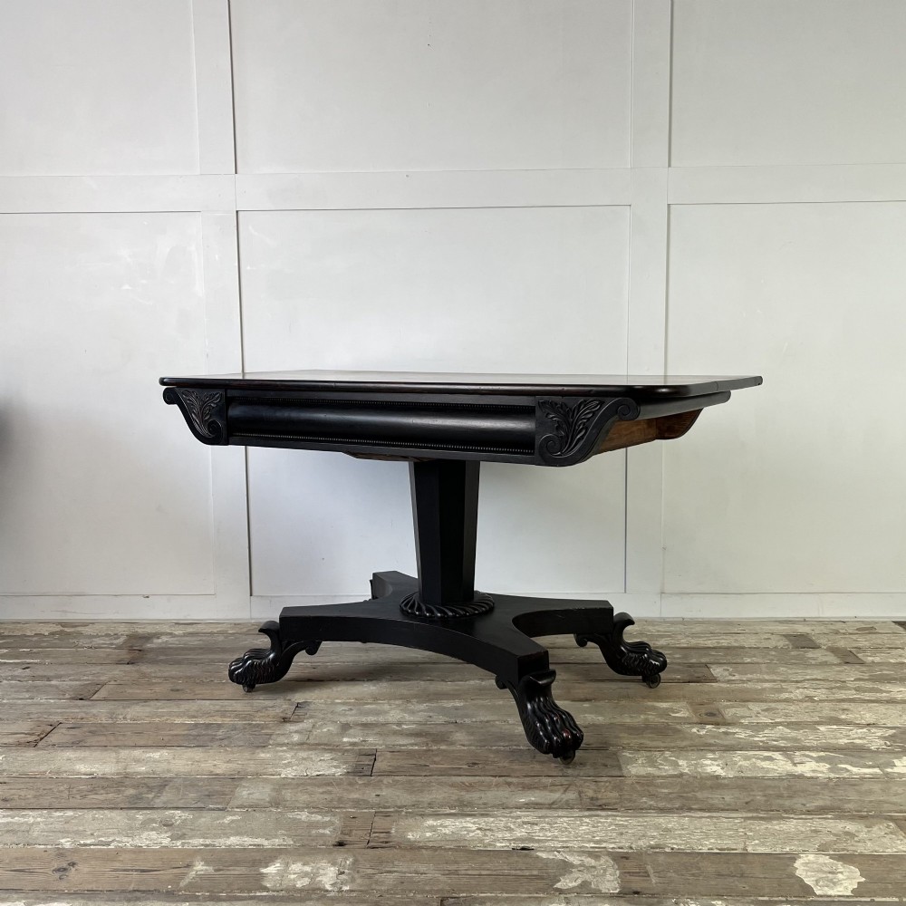 A pair of William IV ebonised mahogany console tables with polished mahogany tops, central pedestal columns, and carved claw feet on brass castors. View II