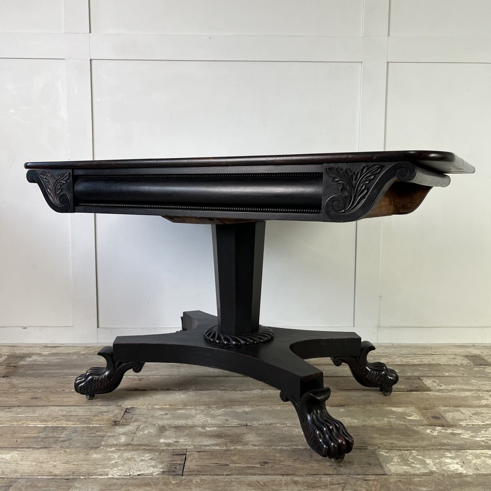 A pair of William IV ebonised mahogany console tables with polished mahogany tops, central pedestal columns, and carved claw feet on brass castors. View III