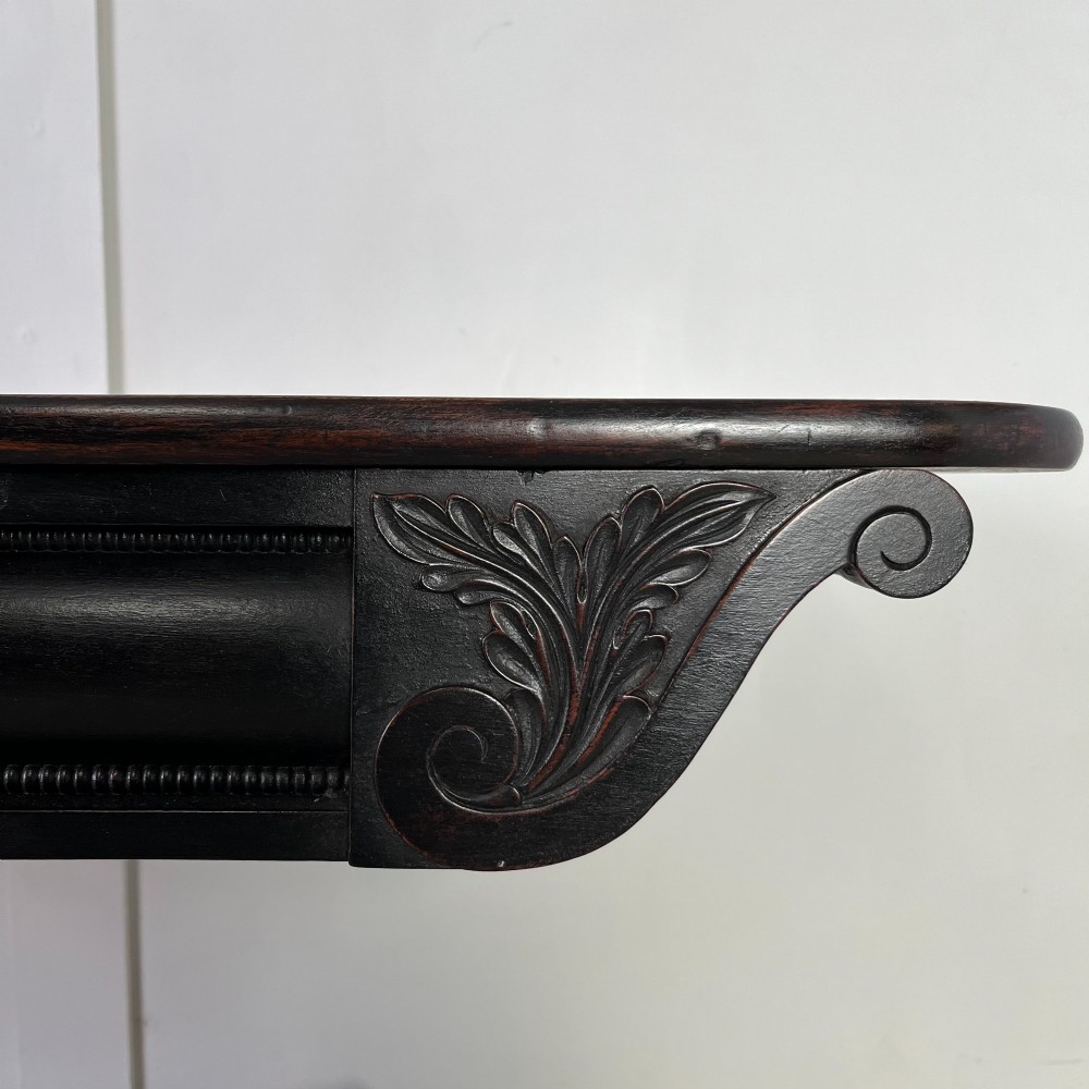 A pair of William IV ebonised mahogany console tables with polished mahogany tops, central pedestal columns, and carved claw feet on brass castors. View VII