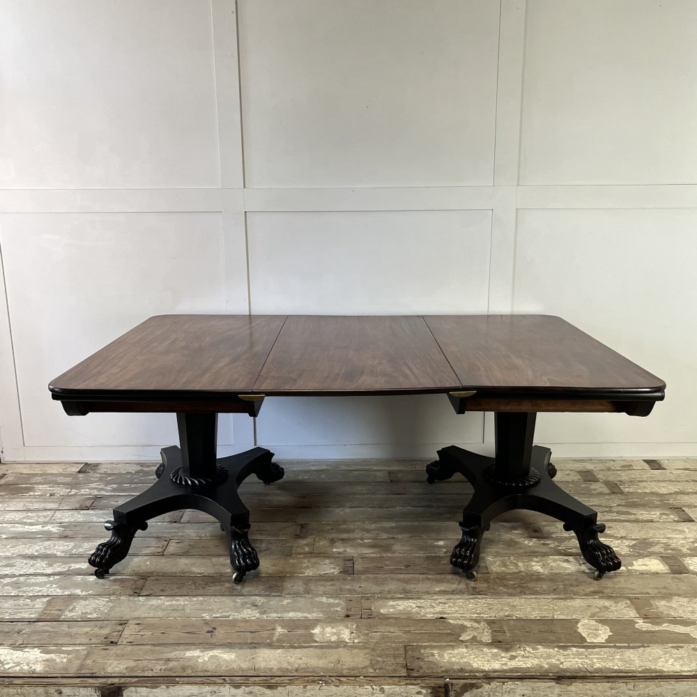 A pair of William IV ebonised mahogany console tables with polished mahogany tops, central pedestal columns, and carved claw feet on brass castors. View XI