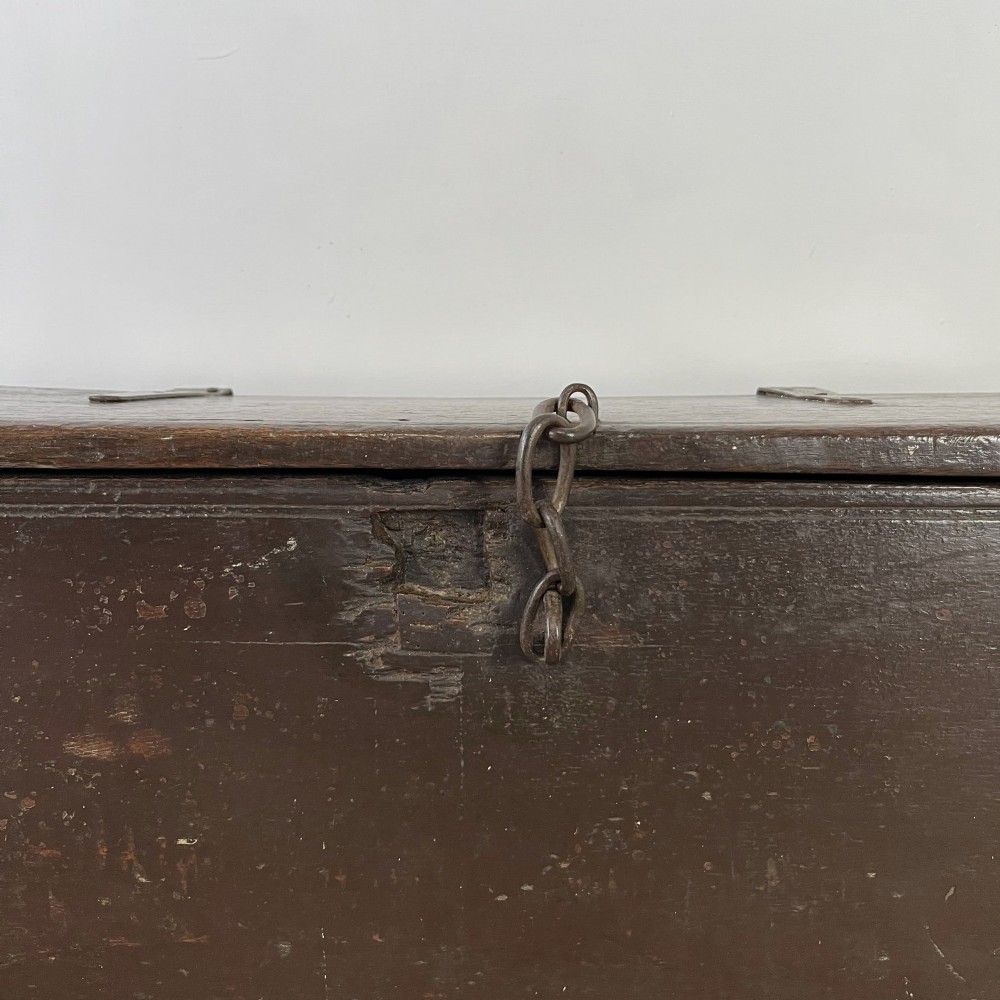 A dark brown 18th-century oak coffer with a flat hinged lid, iron hardware, and slab end supports. View III
