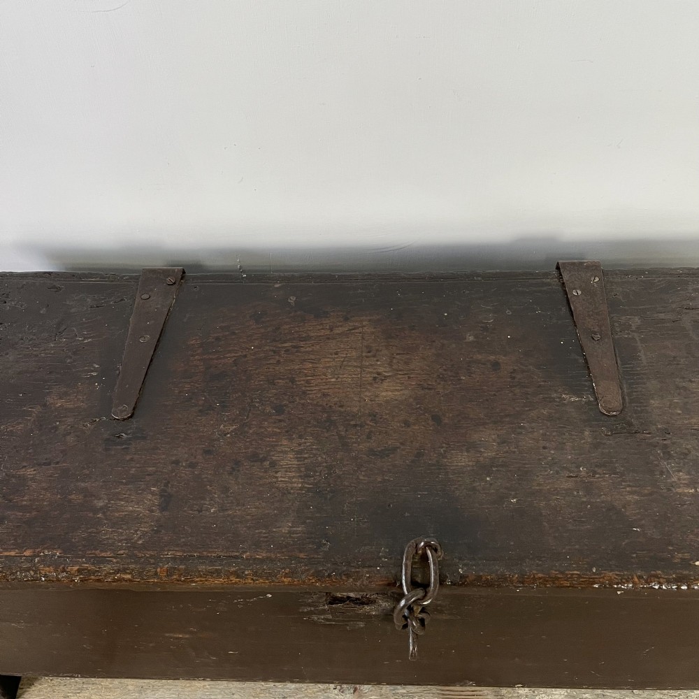 A dark brown 18th-century oak coffer with a flat hinged lid, iron hardware, and slab end supports. View IV