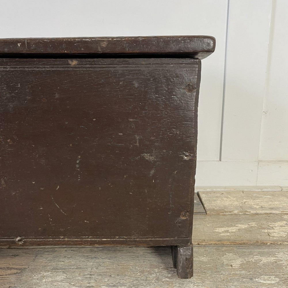 A dark brown 18th-century oak coffer with a flat hinged lid, iron hardware, and slab end supports. View VII