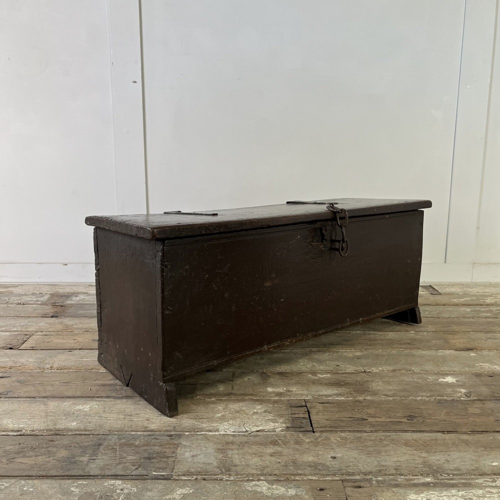 A dark brown 18th-century oak coffer with a flat hinged lid, iron hardware, and slab end supports. View VIII