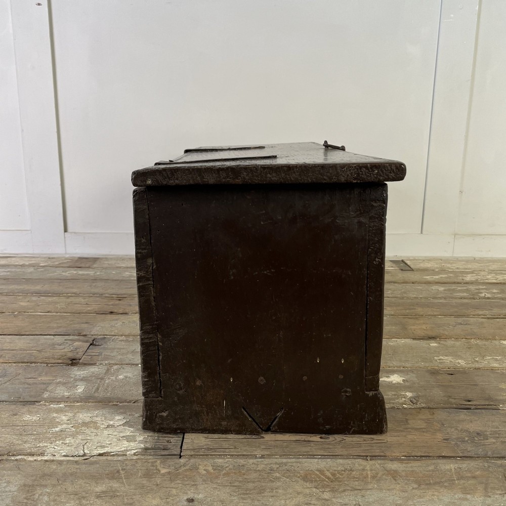 A dark brown 18th-century oak coffer with a flat hinged lid, iron hardware, and slab end supports. View IX