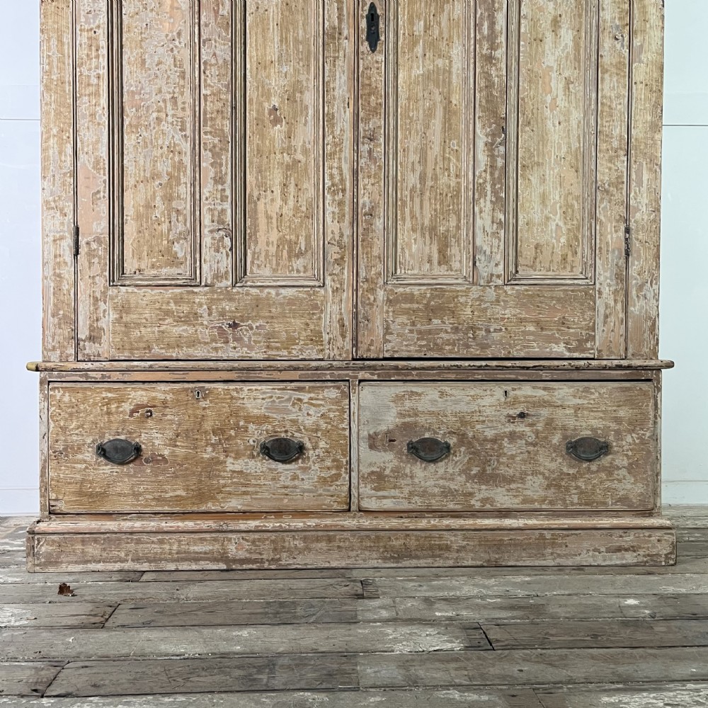 A tall Victorian pine housekeepers cupboard with distressed cream painted finish, double panelled doors, and two bottom drawers. View III