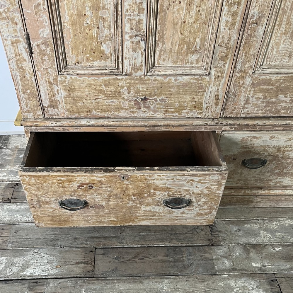 A tall Victorian pine housekeepers cupboard with distressed cream painted finish, double panelled doors, and two bottom drawers. View IV