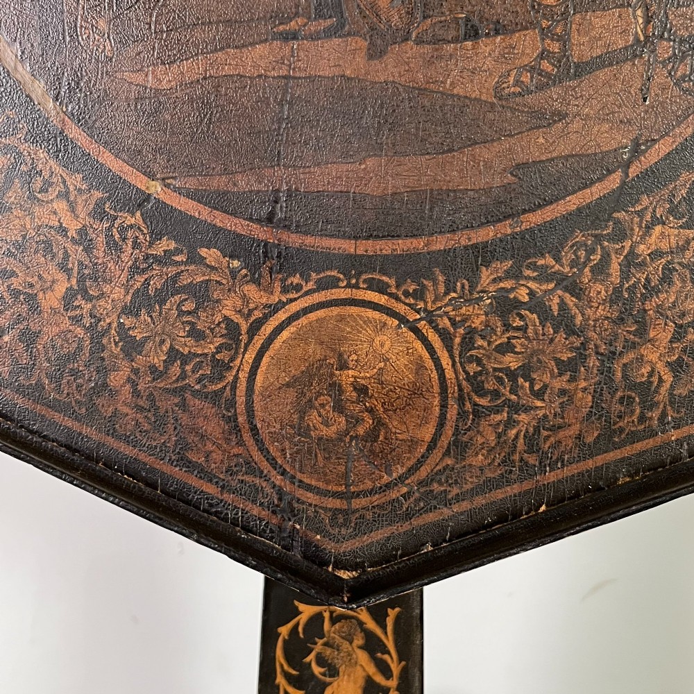 An early nineteenth-century octagonal ebonised tilt-top table featuring intricate ink-drawn classical figures and floral penwork borders. View III