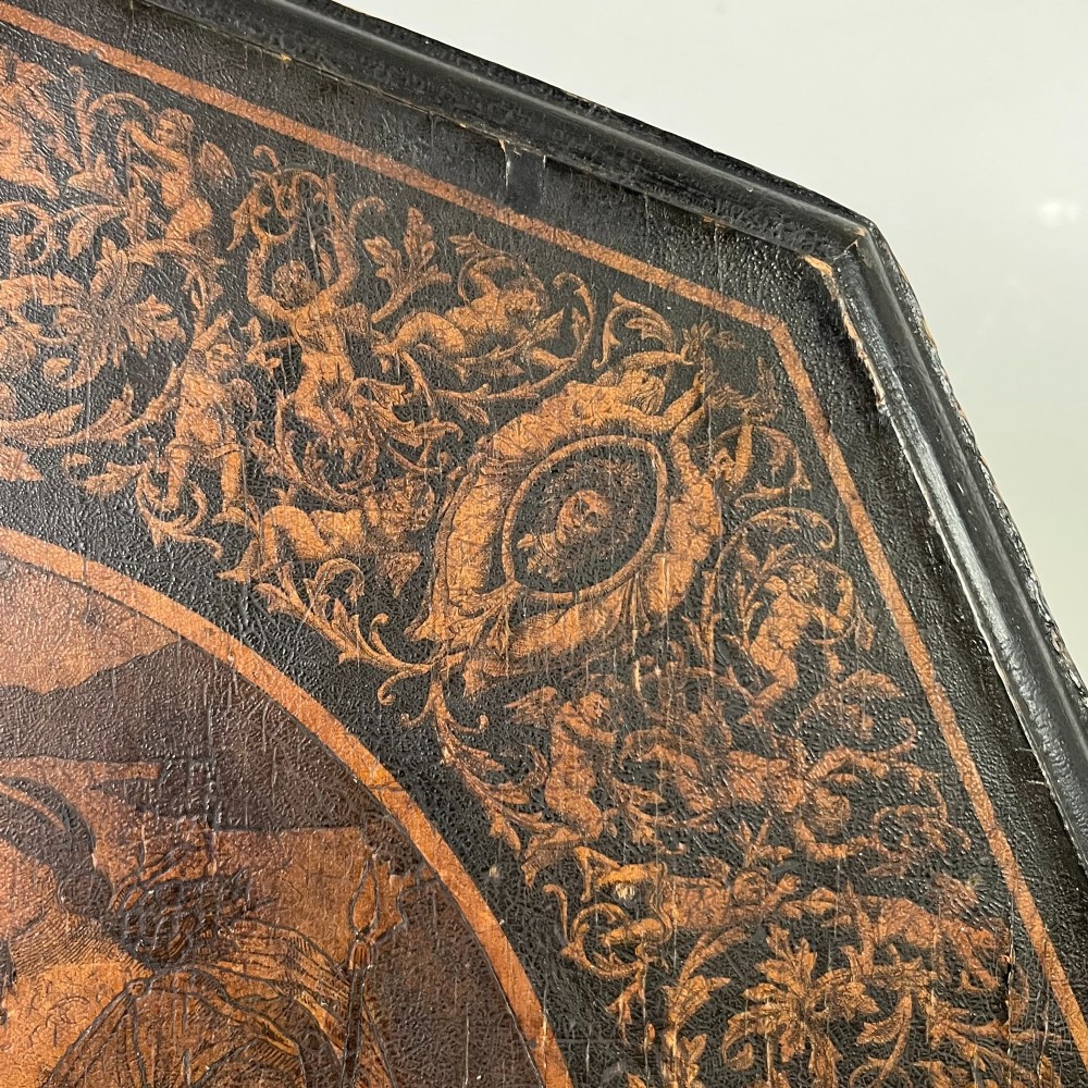 An early nineteenth-century octagonal ebonised tilt-top table featuring intricate ink-drawn classical figures and floral penwork borders. View IV