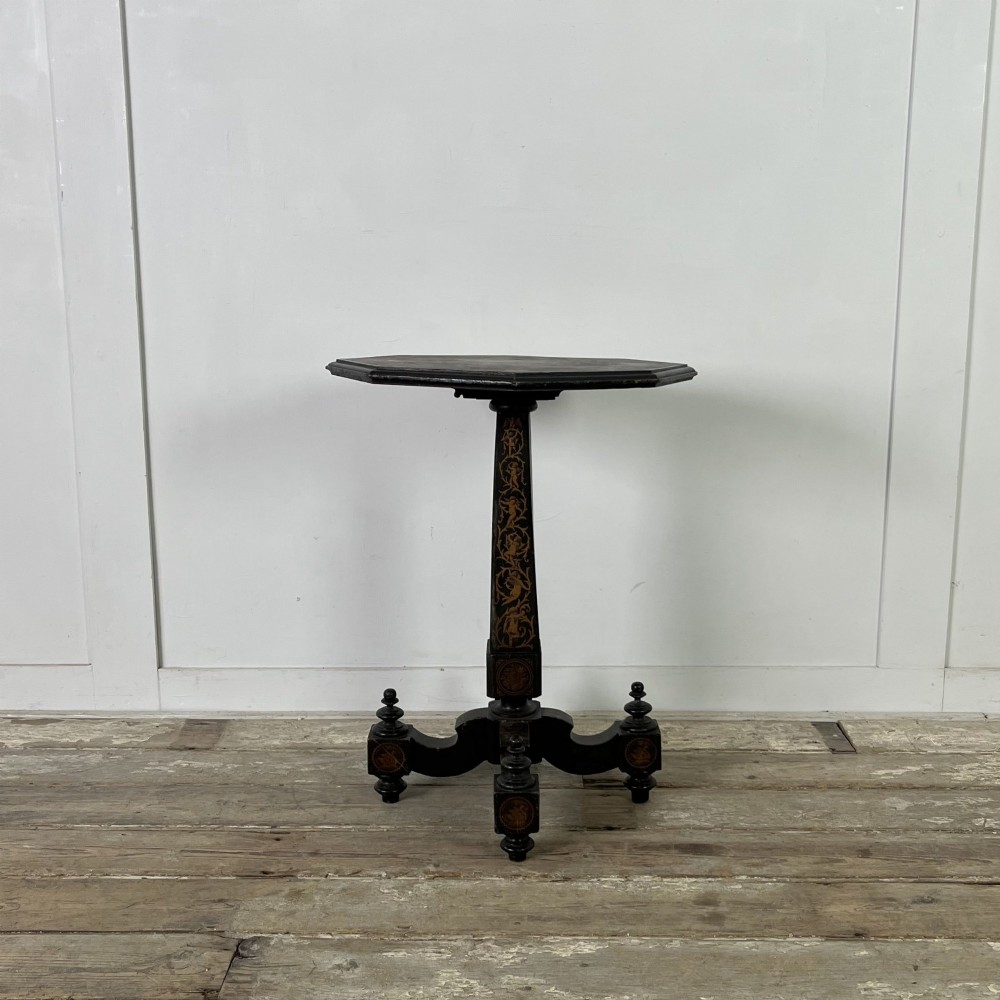 An early nineteenth-century octagonal ebonised tilt-top table featuring intricate ink-drawn classical figures and floral penwork borders. View XI