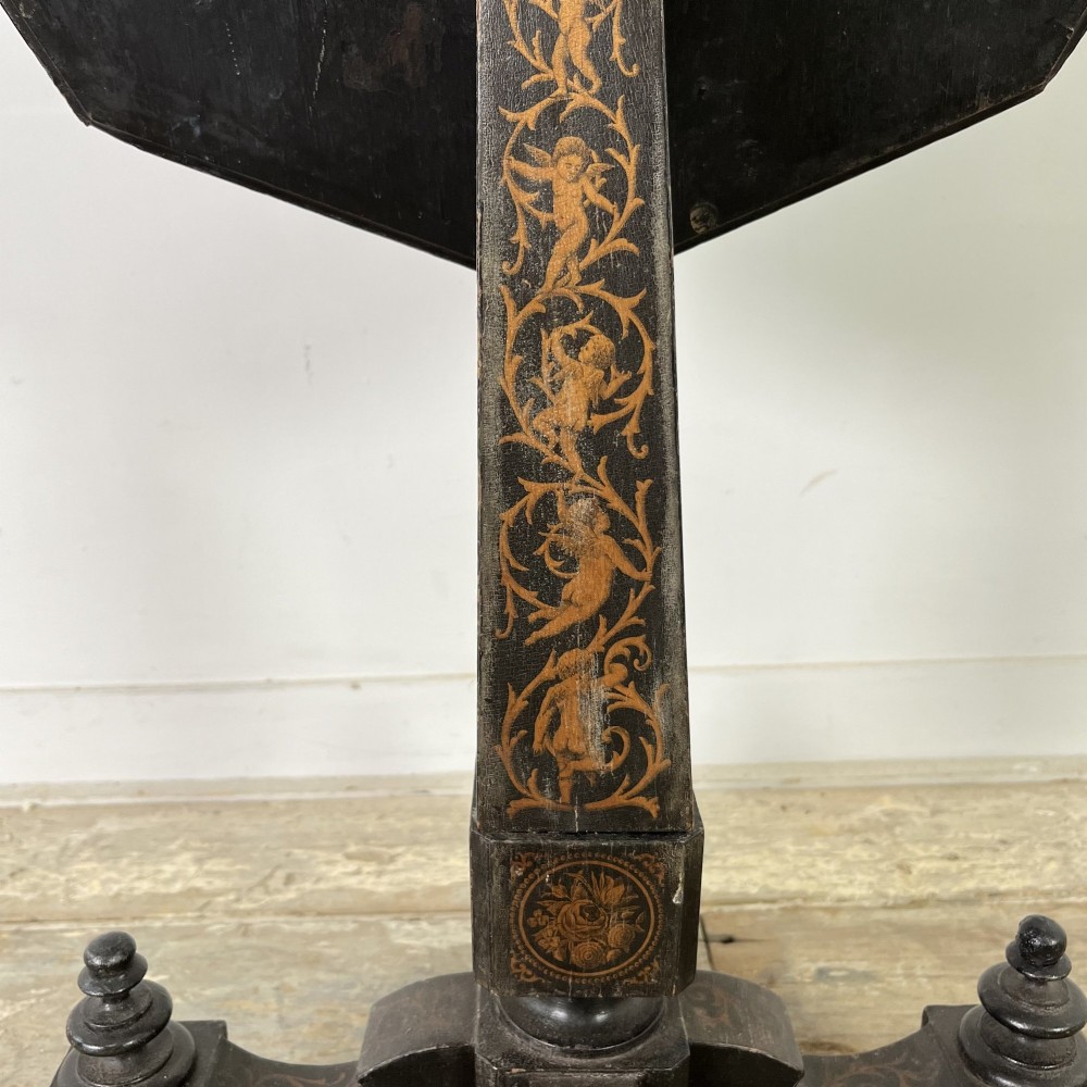 An early nineteenth-century octagonal ebonised tilt-top table featuring intricate ink-drawn classical figures and floral penwork borders. View XII