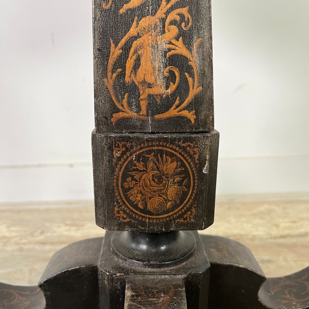 An early nineteenth-century octagonal ebonised tilt-top table featuring intricate ink-drawn classical figures and floral penwork borders. View XIV
