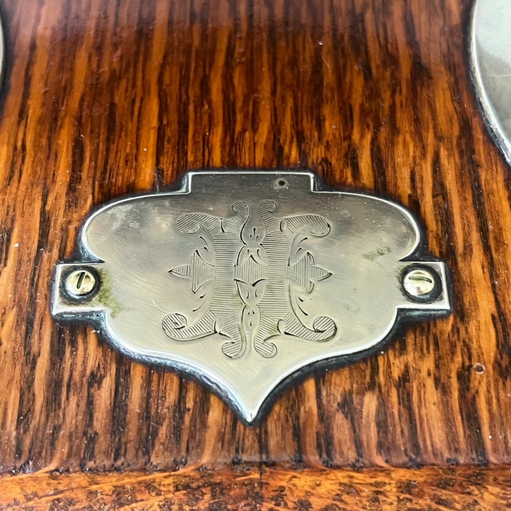 A Victorian tabletop dinner gong featuring two curved natural horns mounted on a polished oak base, holding a central hammered brass disc with an accompanying wooden striker. View V