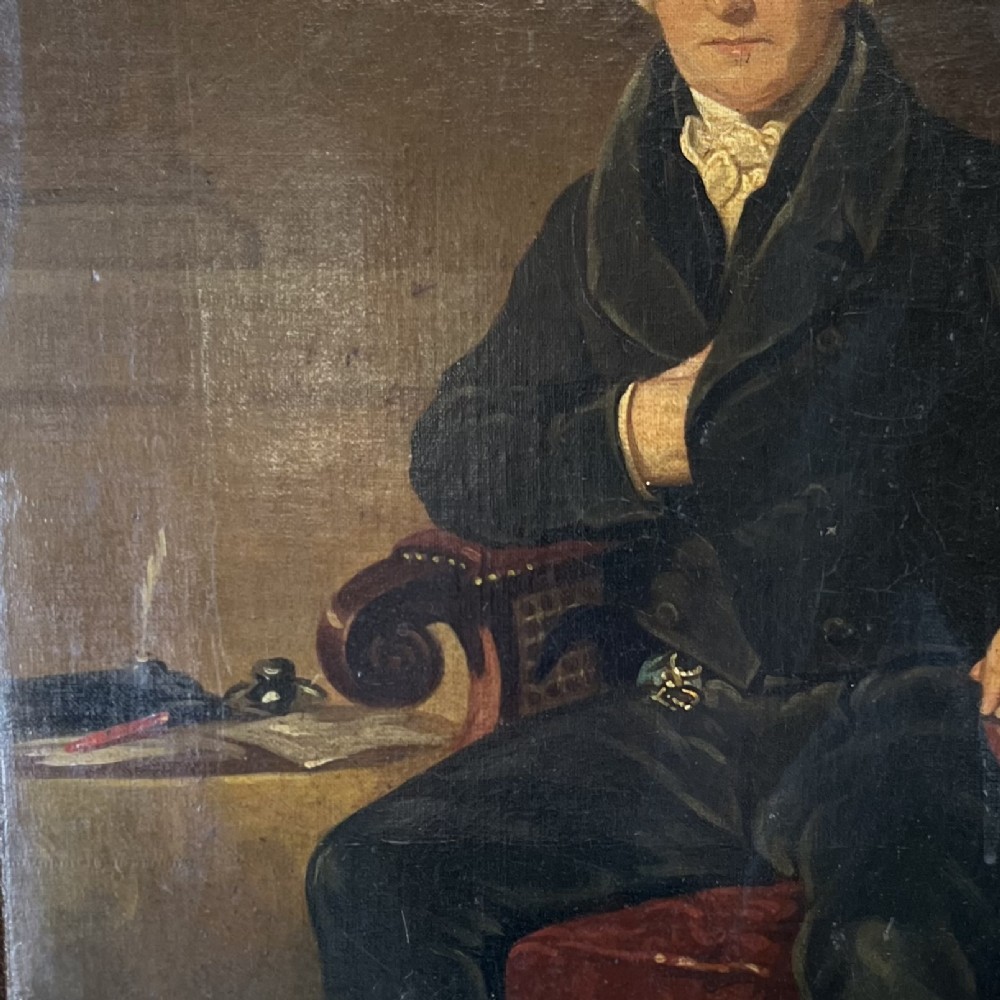 A 19th-century oil portrait depicting a seated gentleman in dark attire against a dark background, set within a heavily carved giltwood frame. View V