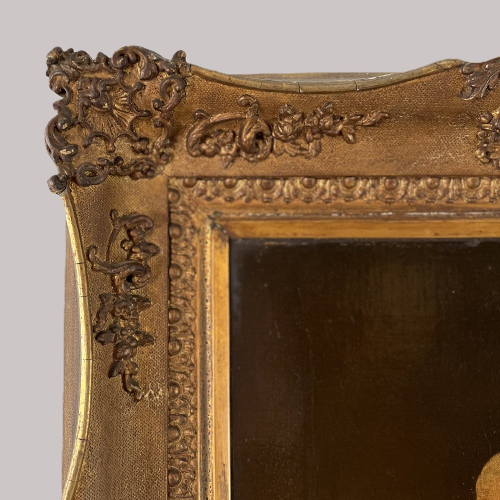 A 19th-century oil portrait depicting a seated gentleman in dark attire against a dark background, set within a heavily carved giltwood frame. View X