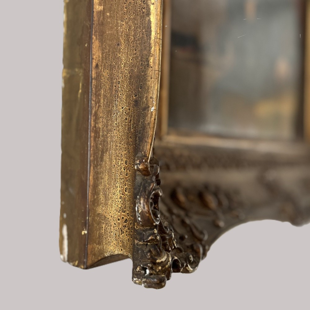 A 19th-century oil portrait depicting a seated gentleman in dark attire against a dark background, set within a heavily carved giltwood frame. View XII