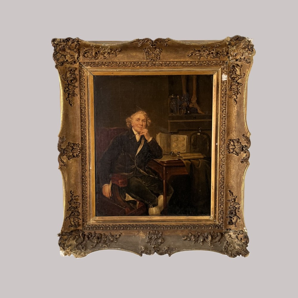 A nineteenth-century oil portrait depicting a seated gentleman resting his chin on his hand, presented in an elaborate gilded swept frame.