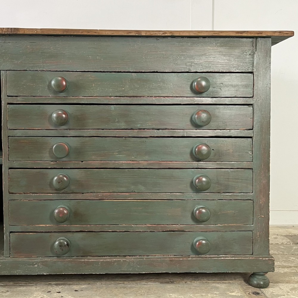 A low Victorian dark green painted pine artist chest featuring six shallow drawers on the right, an open shelf compartment on the left, and an unpainted timber top. View III