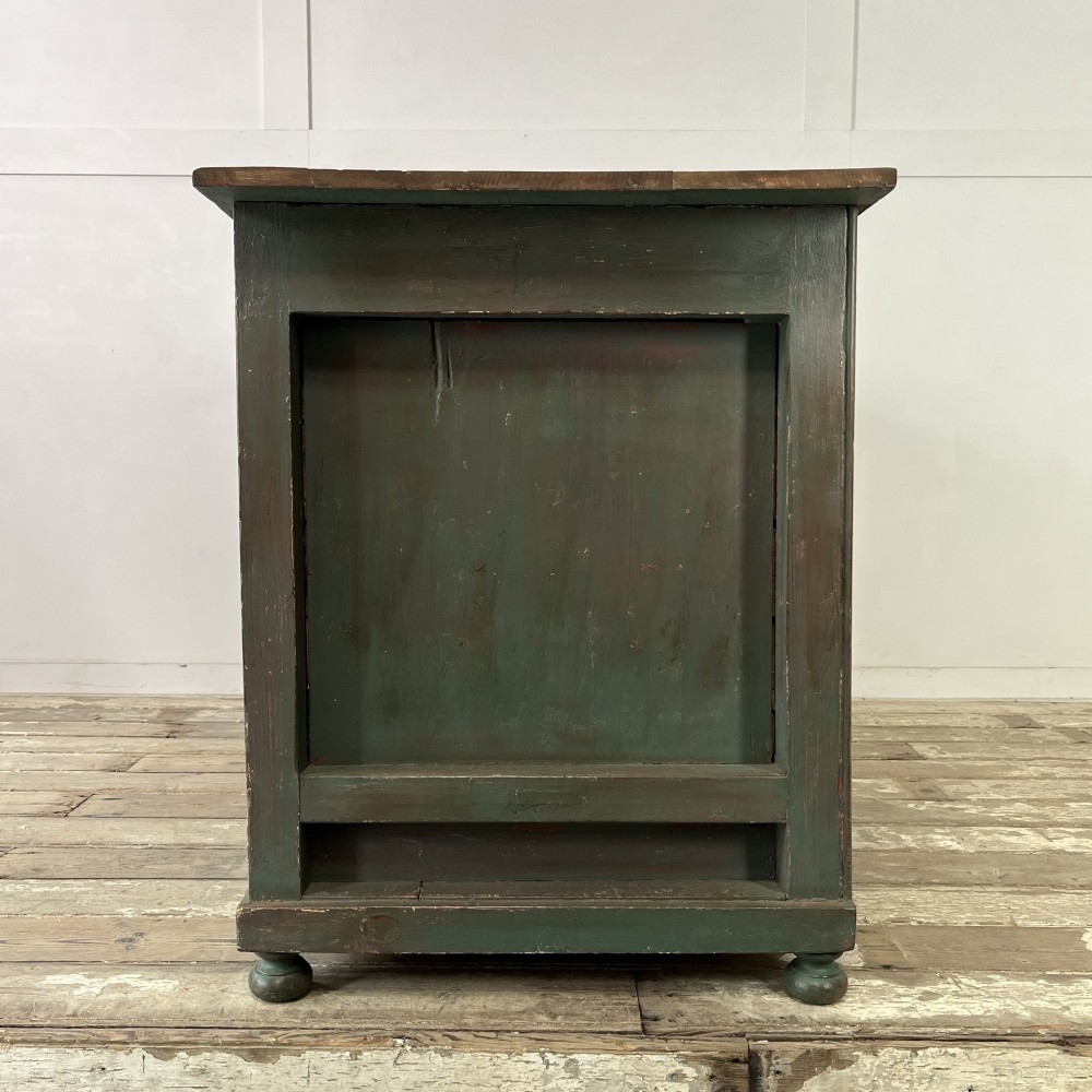 A low Victorian dark green painted pine artist chest featuring six shallow drawers on the right, an open shelf compartment on the left, and an unpainted timber top. View XII