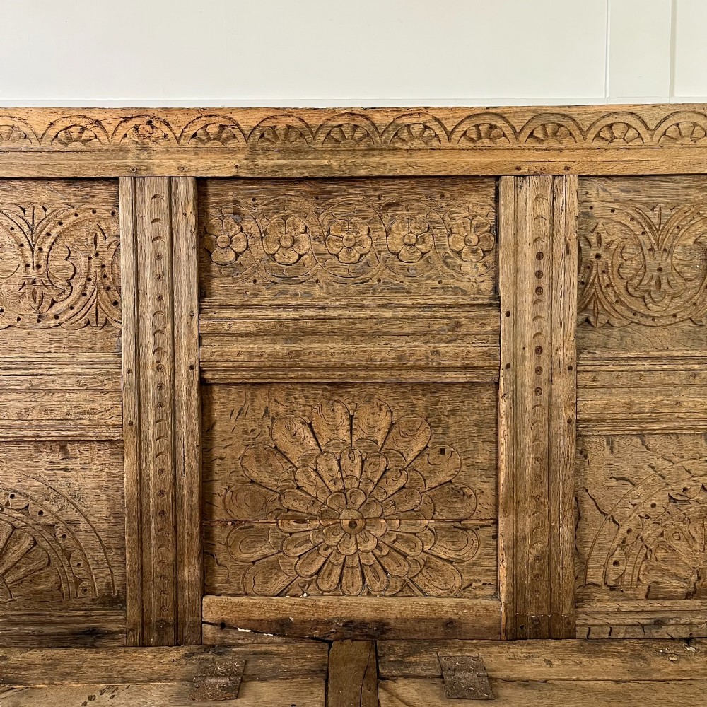 An early nineteenth-century carved oak high-back settle featuring carved back panels, curved arms, and an integrated box storage seat. View VI