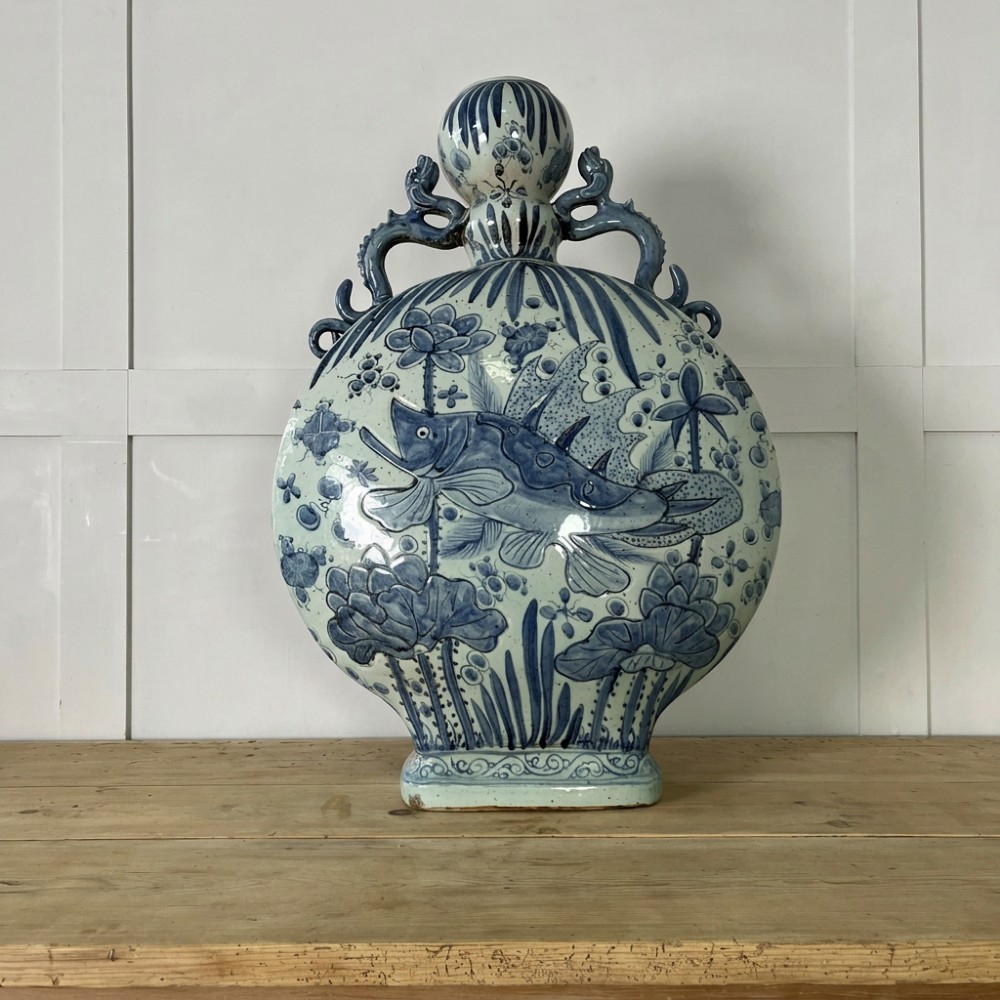 An extra large blue and white Chinese style porcelain moon flask decorated with a carp among lotus blossoms and styled with twin dragon handles.