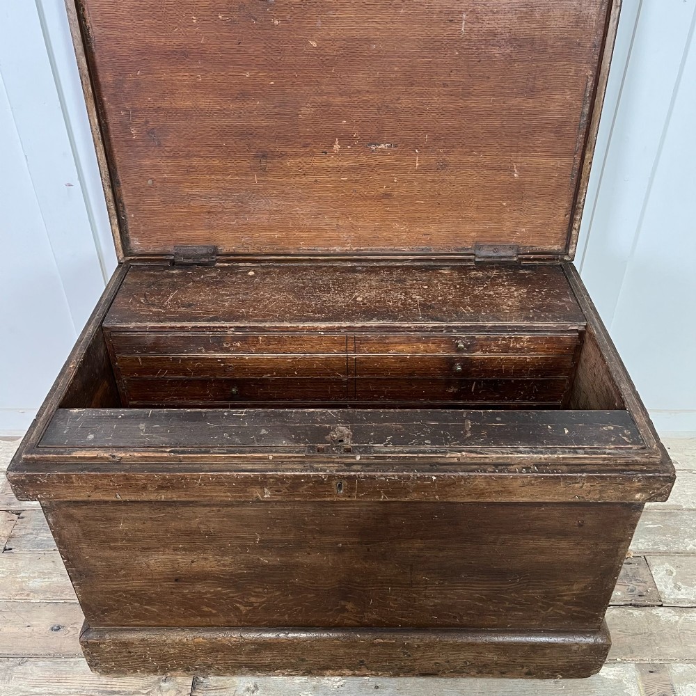 An early 20th-century pine carpenters chest featuring an upper hinged lid and multiple shallow lower drawers with small round knobs. View IV