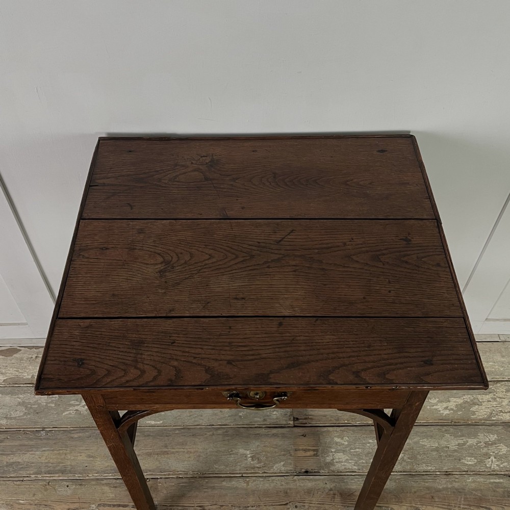An early 19th century dark oak side table featuring a single drawer with a brass handle, arched aprons, and straight square legs connected by a low stretcher. View III