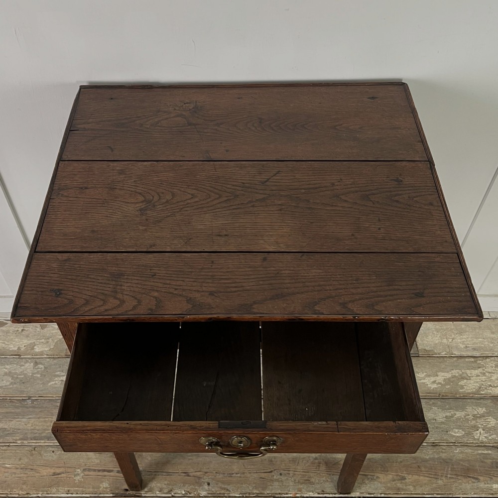 An early 19th century dark oak side table featuring a single drawer with a brass handle, arched aprons, and straight square legs connected by a low stretcher. View IV