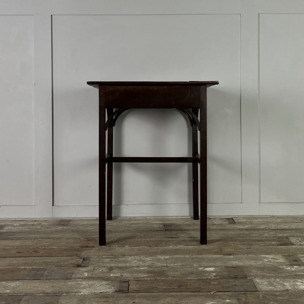 An early 19th century dark oak side table featuring a single drawer with a brass handle, arched aprons, and straight square legs connected by a low stretcher. View VII