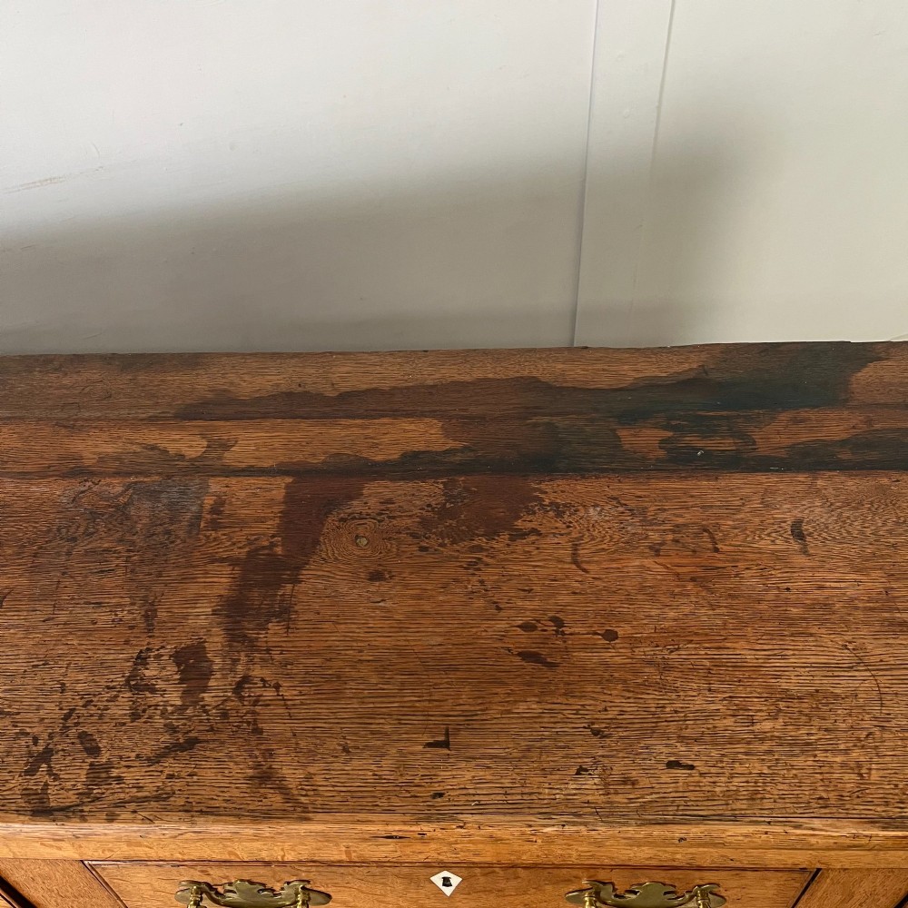 An early nineteenth-century oak kitchen dresser featuring an open upper plate rack over a base with central drawers and side cupboard doors with brass hardware. View XIV