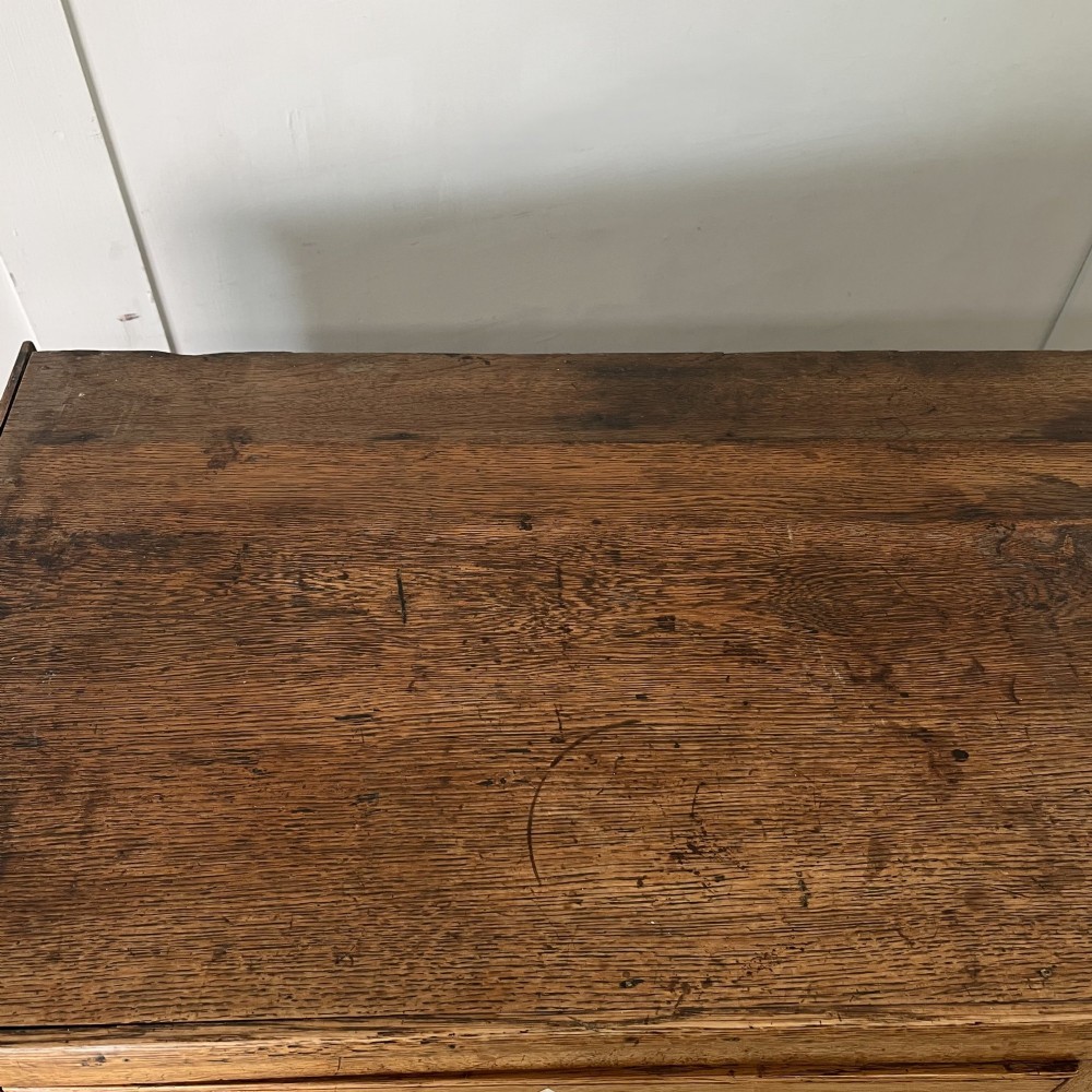 An early nineteenth-century oak kitchen dresser featuring an open upper plate rack over a base with central drawers and side cupboard doors with brass hardware. View XV