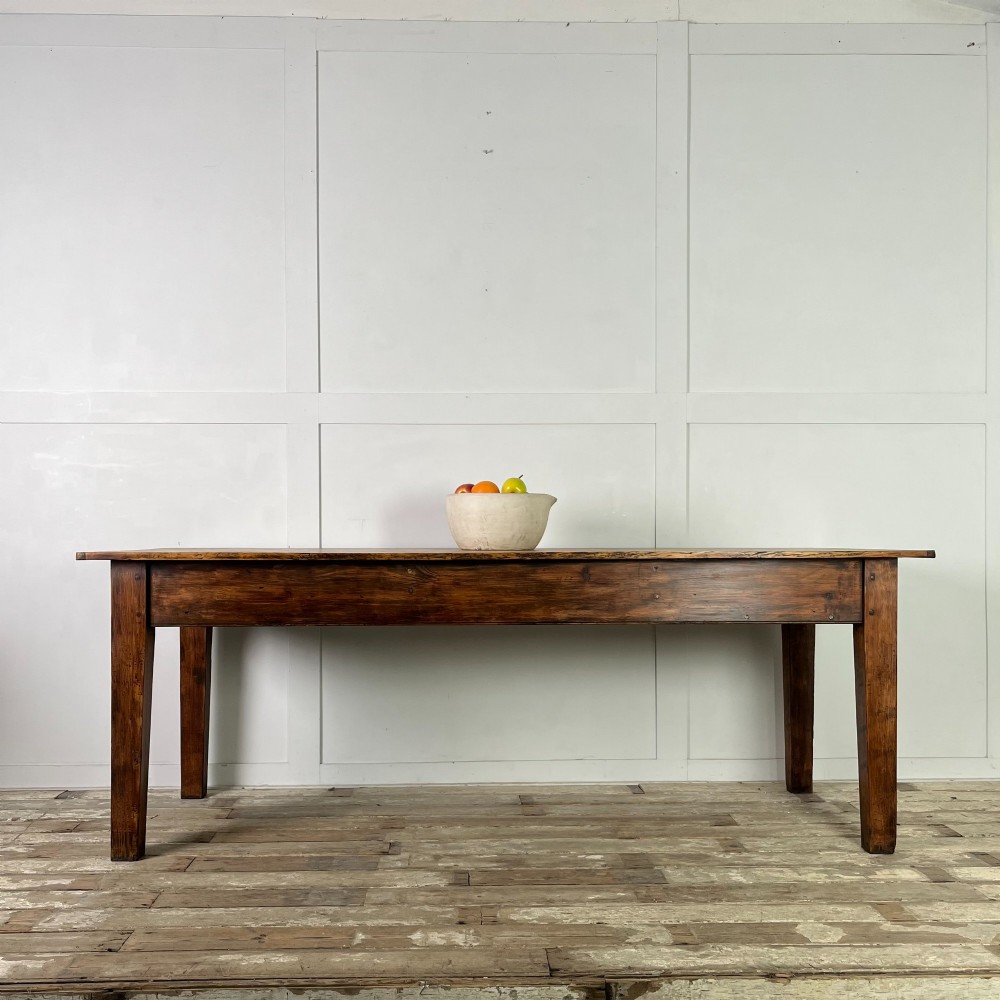A long 19th-century pine farmhouse dining table with tapered square legs and a warm brown waxed finish.