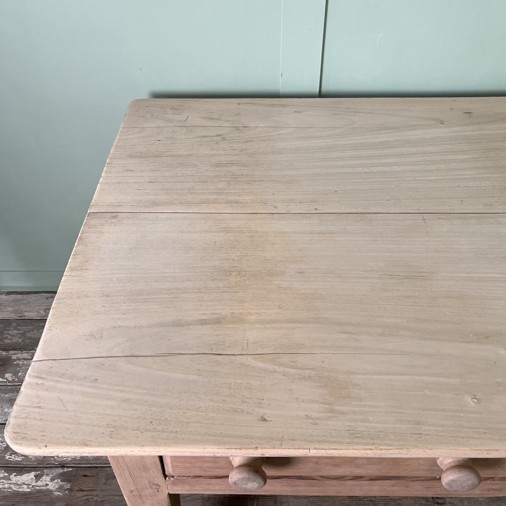 An early nineteenth-century timber prep table featuring three drawers with round wooden knobs set above four tapered legs. View X